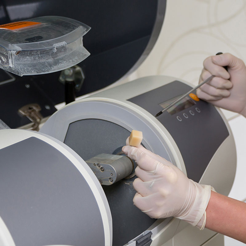 The image shows a person working with a large piece of equipment, possibly a machine for medical or scientific purposes, such as a CT scanner or an MRI device.