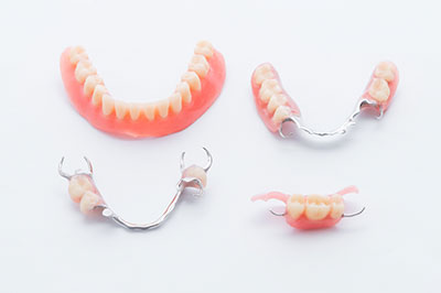 The image displays three pairs of dentures with visible teeth, set against a white background.