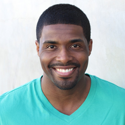 The image shows an elderly couple sitting closely together, with the man on the left smiling broadly at the camera and the woman on the right looking directly ahead with a gentle smile.